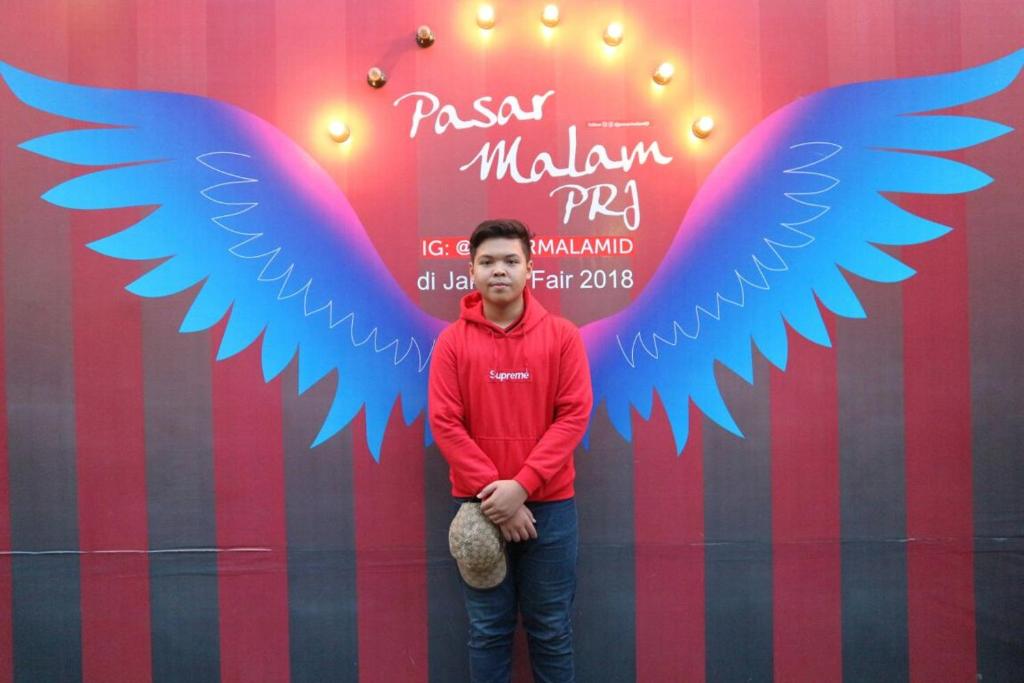 a man standing in front of a wall with blue wings at Rumah Pondok Kelapa 55m Dengan 2 Kamar Tidur in Jakarta