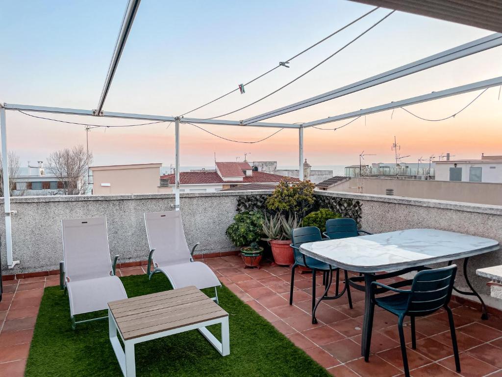 a patio with a table and chairs on a roof at Open Sky, Apartamento con solárium privado y barbacoa in El Vendrell