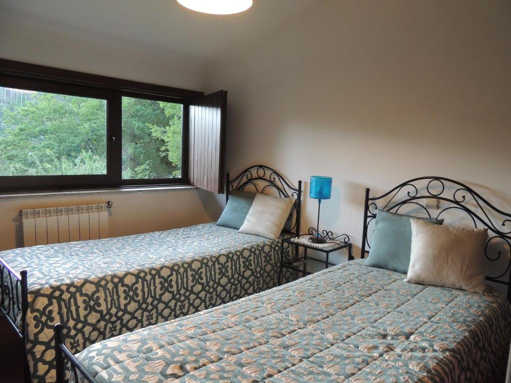 ein Schlafzimmer mit zwei Betten und einem Fenster in der Unterkunft Casa de Férias do Parque da Peneda Gerês in Vila Verde