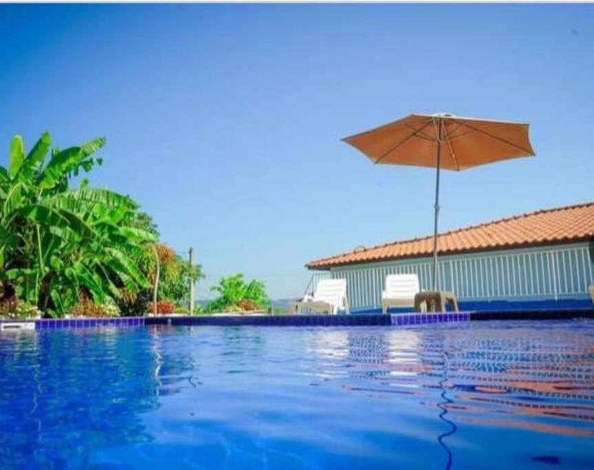 - une piscine avec un parasol, une chaise et une table dans l'établissement Chácara Aloés - suíte com ar cond banheira hidromassagem, à Socorro