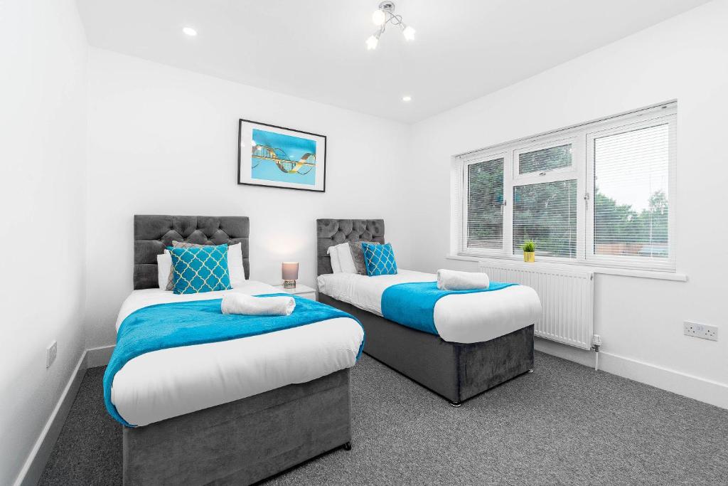 two beds in a room with white walls and windows at 5 Bedroom House - 10 Guests - Multiple off Street Parking - Garden - Smart TV - WIFI - Contractors - Families - Groups 98Q in Birmingham