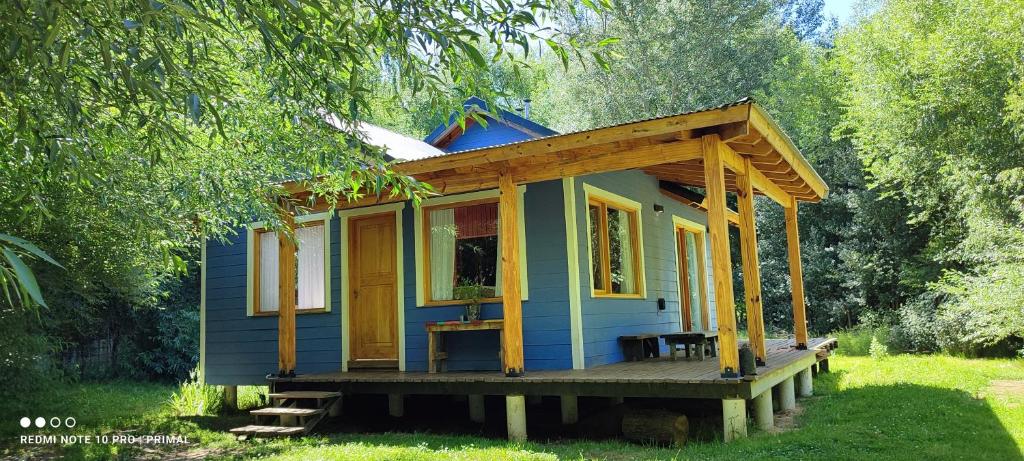 una pequeña casa azul sentada en un porche de madera en Rincon tranquilo en el valle en San Martín de los Andes