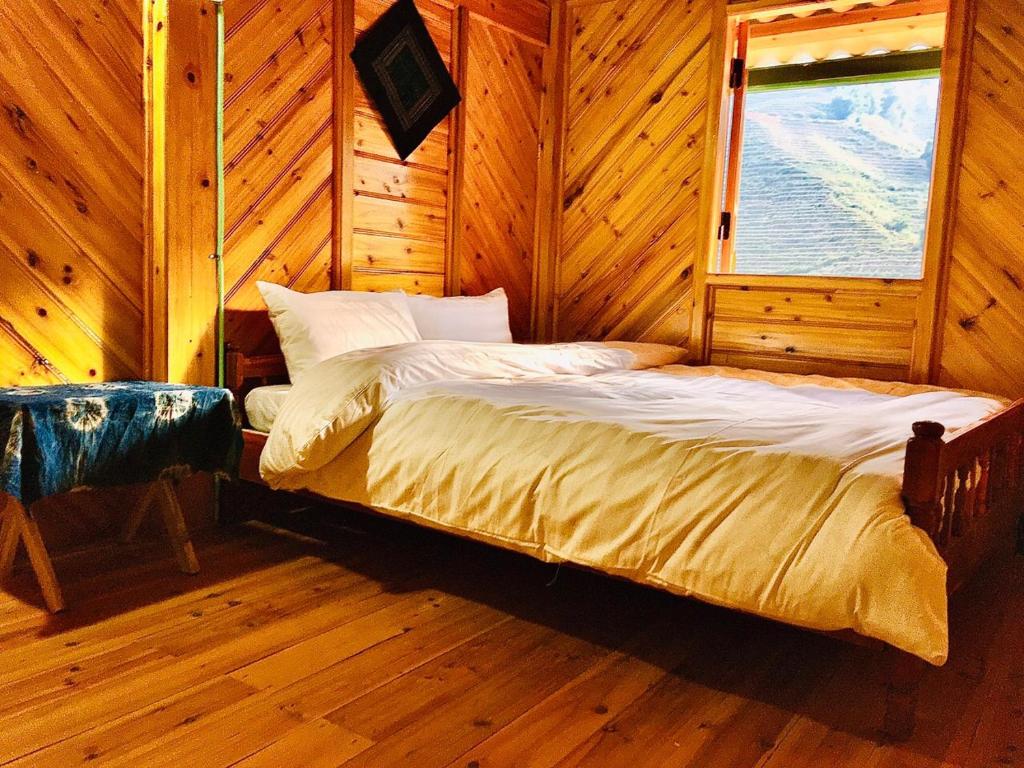 a bed in a wooden room with a window at Lysa House in Lao Cai
