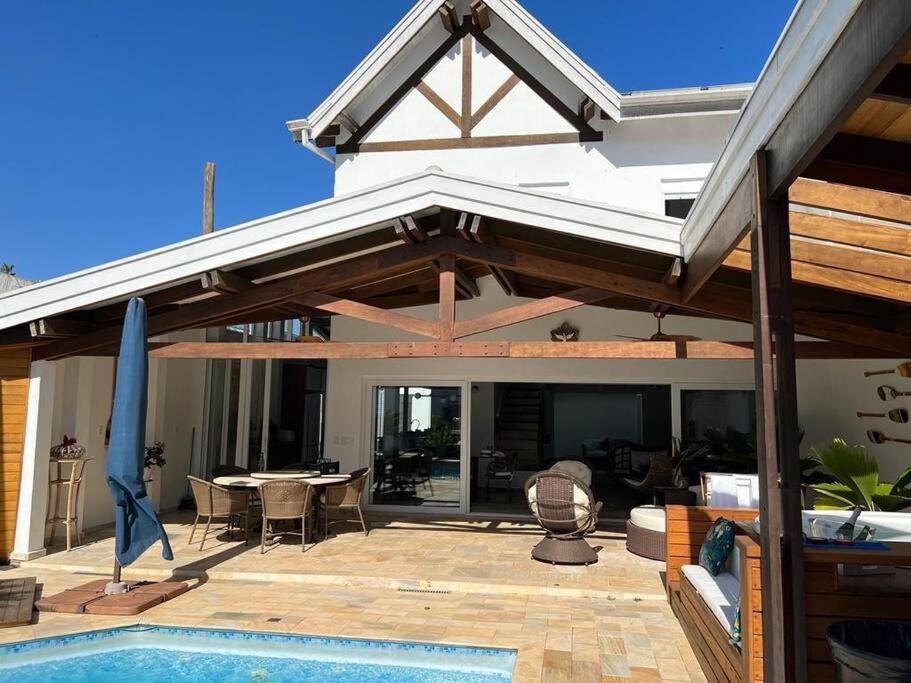 eine offene Terrasse mit einem Tisch und einem Pool in der Unterkunft Linda casa em Barra do Una in São Sebastião