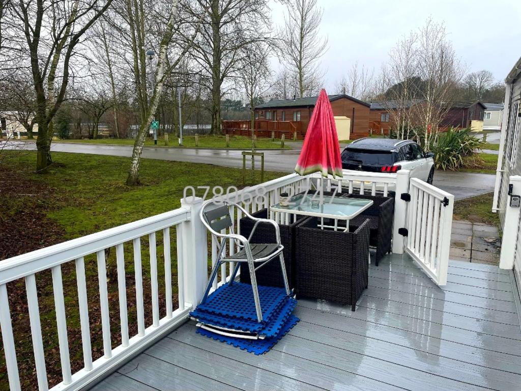 a deck with a table and a red umbrella at J S RETREATS @ TATTERSHALL LAKES in Tattershall