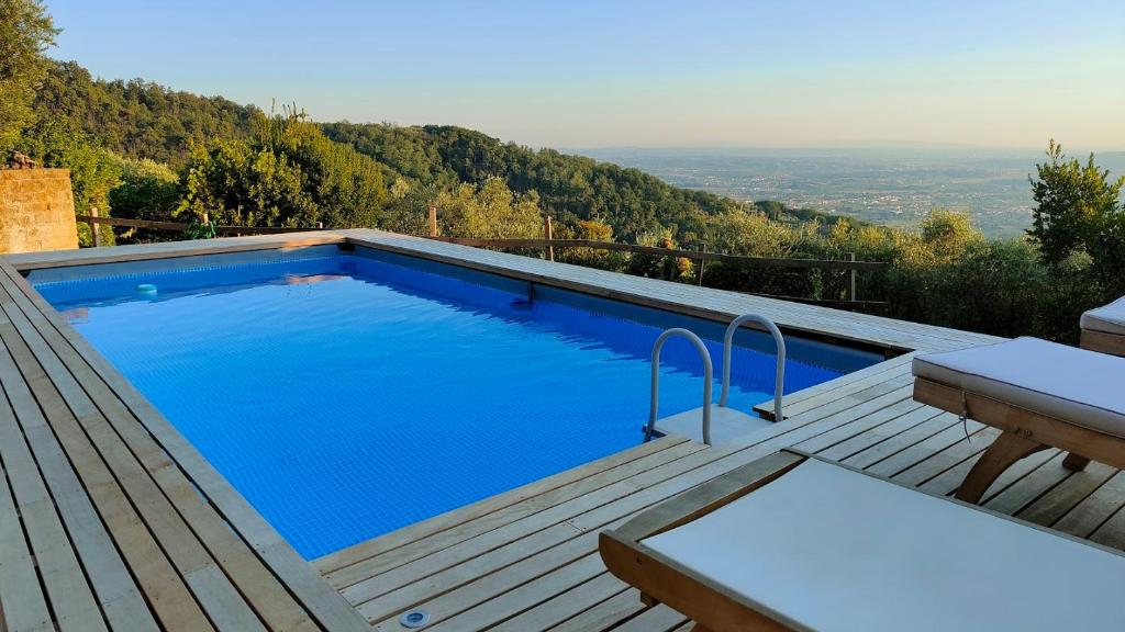 a large swimming pool on a wooden deck with a table at Podere Le Vedute in Larciano