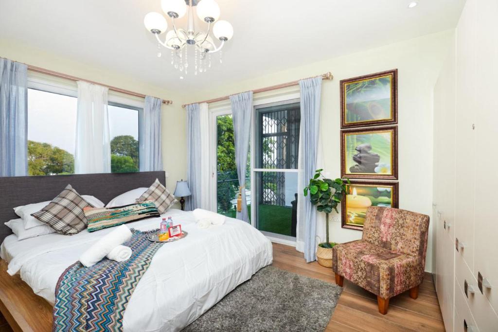 Perfect Luxury @ Henrietta’s Residence في آكرا: غرفة نوم بسرير وكرسي ونوافذ