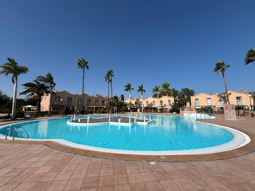 a large swimming pool with palm trees and houses at Canarian Green Oasis by luca properties gran canaria in Maspalomas
