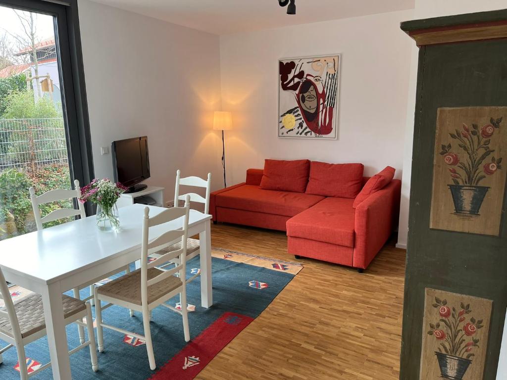 ein Wohnzimmer mit einem roten Sofa und einem Tisch in der Unterkunft Ruhige Ferienwohnung in Oberhaching bei München in Oberhaching