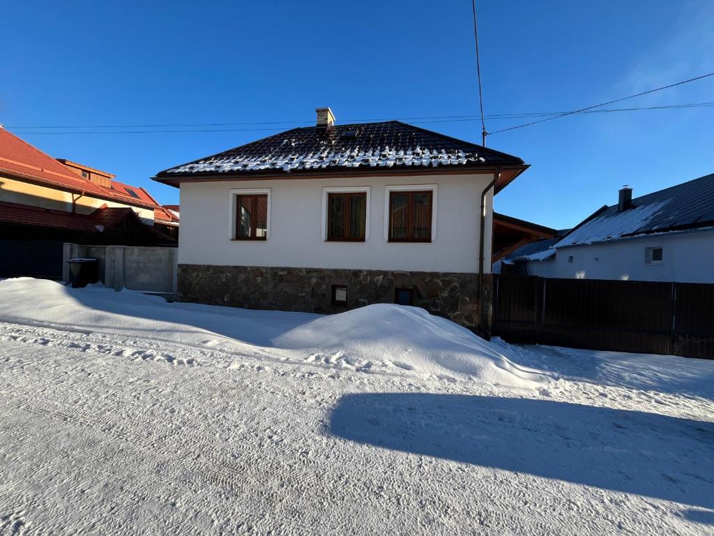 a white house with a black roof in the snow at Chata u Miťa in Telgárt