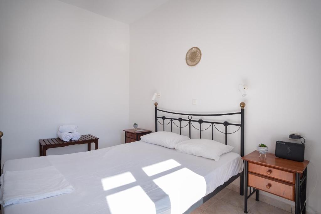 a bedroom with a bed with white sheets and a clock on the wall at Billy's House in Samos