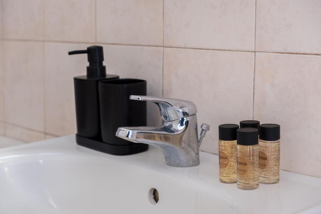 a bathroom sink with a faucet and three bottles at Billy's House in Samos