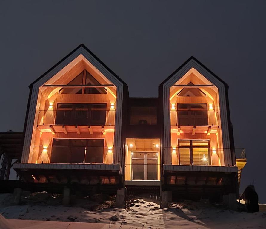 a house with two large windows in the snow at night at Шале Green Land in Bukovel