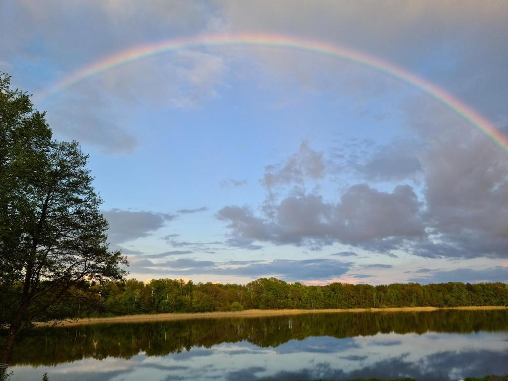 a rainbow in the sky over a lake at Ferienwohnung Prälank direkt am See in Neustrelitz