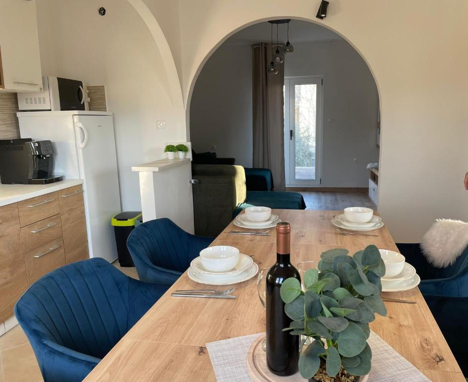 einen Esstisch mit einer Flasche Wein und einer Pflanze in der Unterkunft Jolie Ann Marie apartment in Kaštela