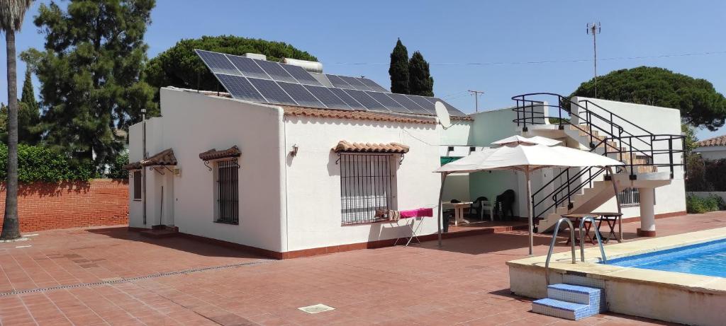 a house with solar panels on the roof next to a swimming pool at Chalet Valdelagrana in El Puerto de Santa María