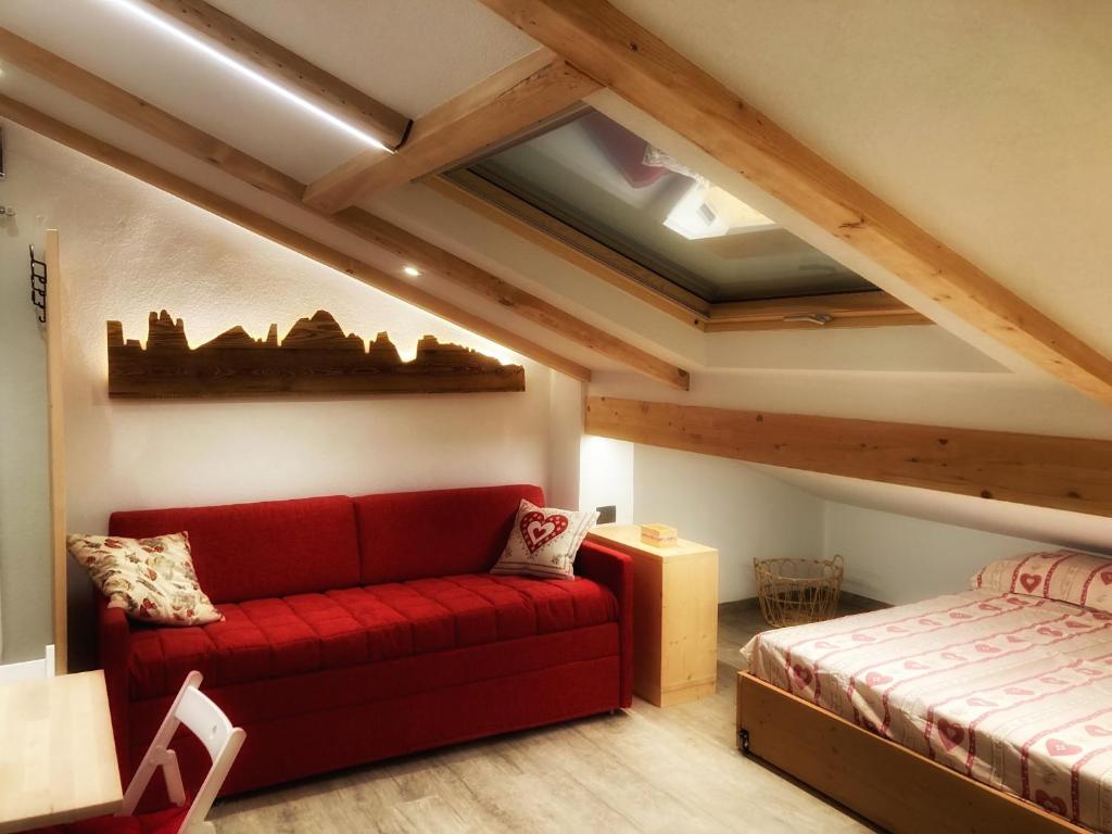 a living room with a red couch and a bed at Ad Alba di Canazei una finestra sulla Marmolada in Alba di Canazei
