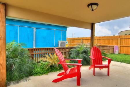 two red chairs sitting on the porch of a house at Spanish Village Siesta Villa in Port Aransas