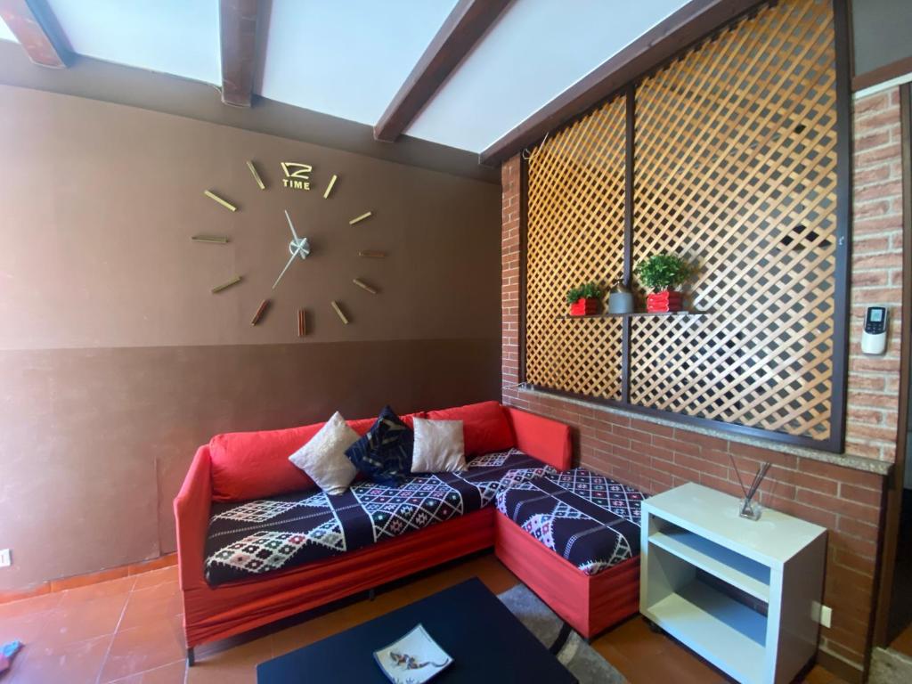 a living room with a red couch and a clock on the wall at Appartamento Homemade in Biella
