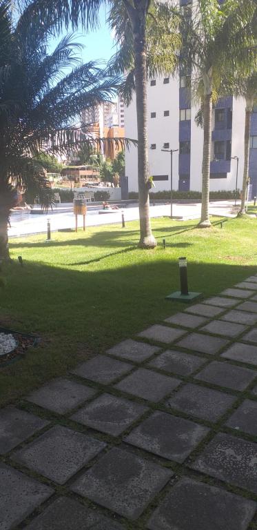 un parque con césped, palmeras y acera en Apartamento mobiliado, en Salvador