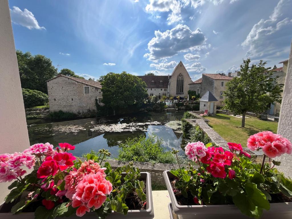 a view of a river from a window with flowers at Les Bruyeres Chambres dhotes et Gite in Verteuil-sur-Charente
