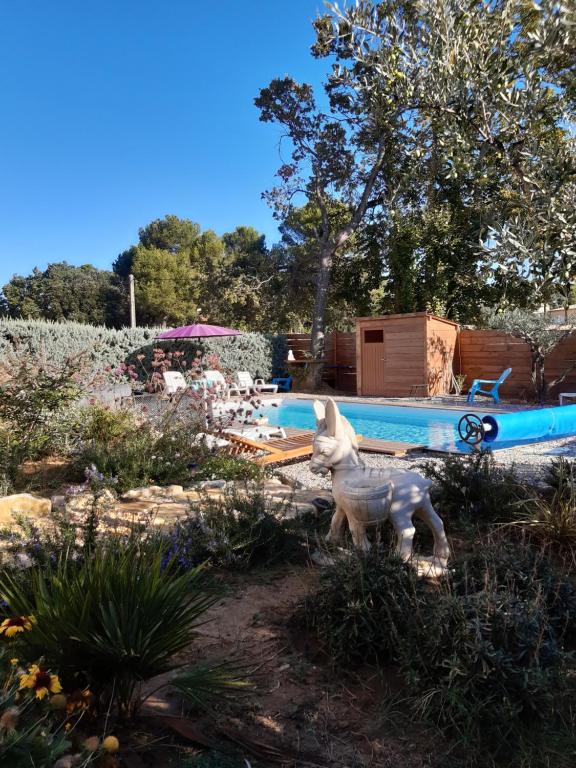 une statue d'un chien dans une cour à côté d'une piscine dans l'établissement L' Ariston, à Vaison-la-Romaine