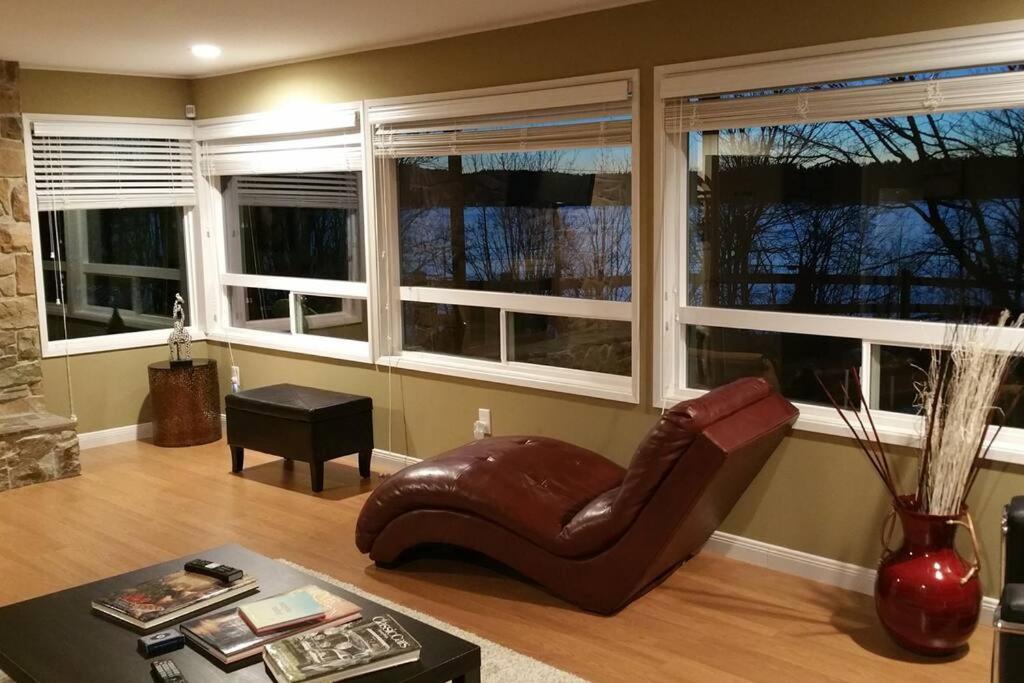 una sala de estar con una silla de cuero y ventanas en C19 Conscious, QUIET, ADULT Lake View Rental, en Sammamish