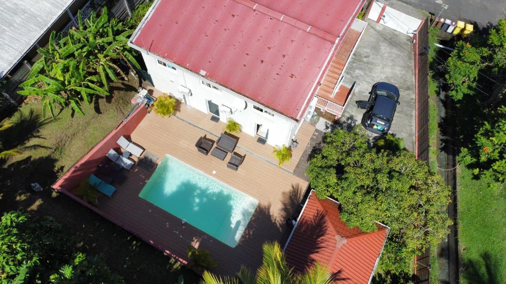 Cette chambre offre une vue sur une maison dotée d'une piscine et d'un toit rouge. dans l'établissement Résidence Belle Anse 6 Pers 3ilets, à Les Trois-Îlets