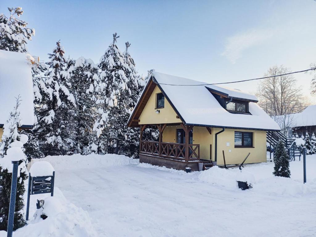 uma pequena casa amarela com neve em Domki Spokojny Zakątek em Lipowa