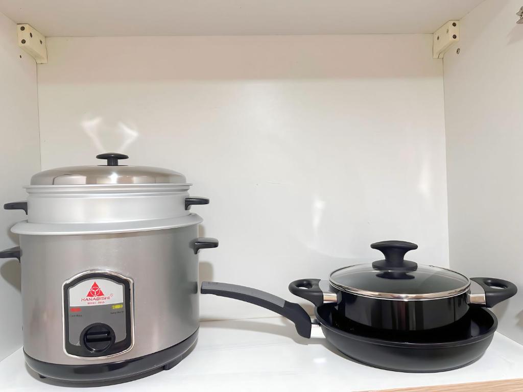 a slow cooker and a pot on a stove at Condo Unit near MOA, PICC, US Embassy and Airport in Manila