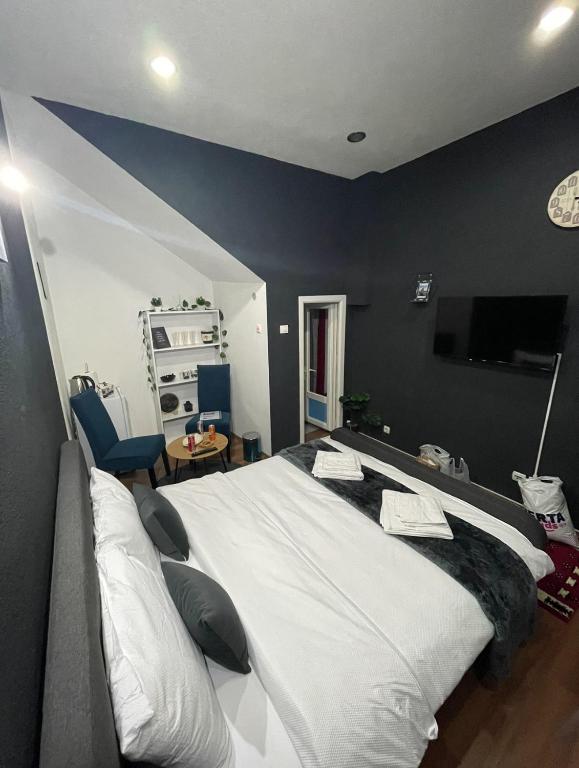 um quarto com uma grande cama branca com paredes azuis em London.Apartments em Pristina