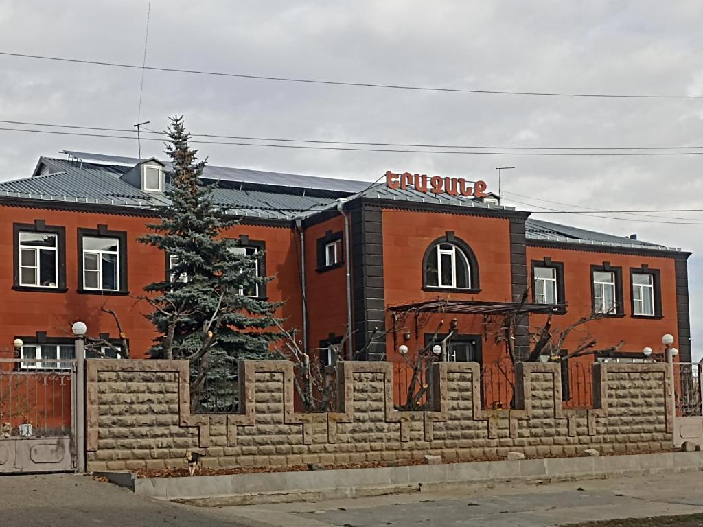 a brick building with a fence in front of it at Erazank Hotel in Gyumri
