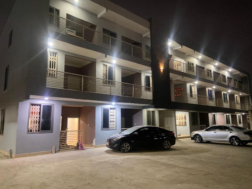 Magic City Apartments في Kasoa: سيارتين متوقفتين أمام مبنى في الليل