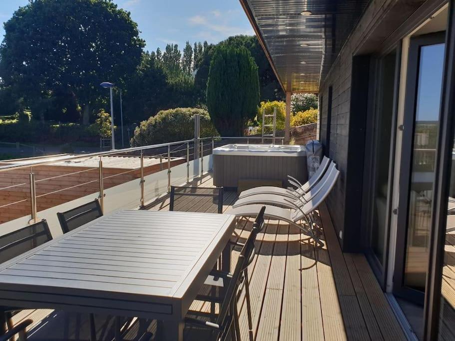terraza de madera con mesa y sillas en el balcón en Gîte de l&#39;Estuaire classé 3 étoiles, en Lézardrieux