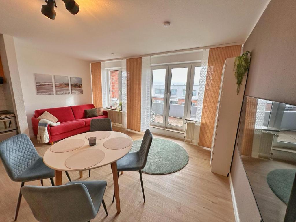uma sala de estar com uma mesa e cadeiras e um sofá vermelho em Watt & Wind - Tolles Schwimmbad em Cuxhaven