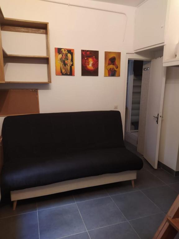 - un canapé noir dans une pièce avec des photos sur le mur dans l'établissement Le 4, à Paris