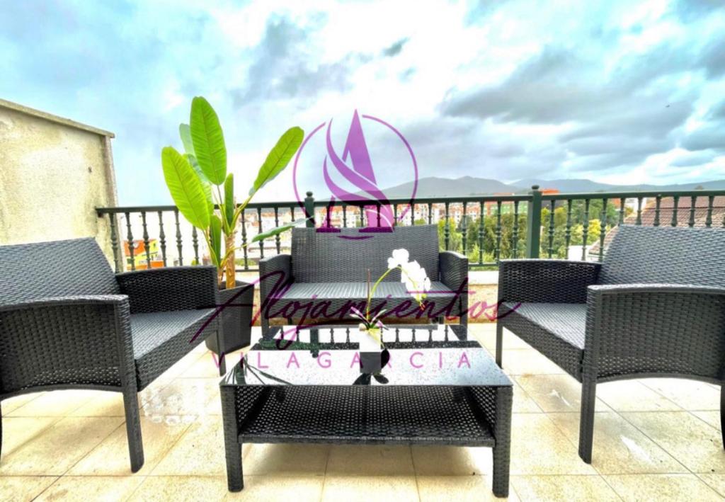 Un patio con sillas y una mesa en el balcón. en Ático Doctor Fleming, en Vilagarcía de Arousa