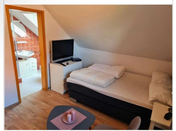 een kleine slaapkamer met een bed en een televisie bij Messezimmer in Edemissen