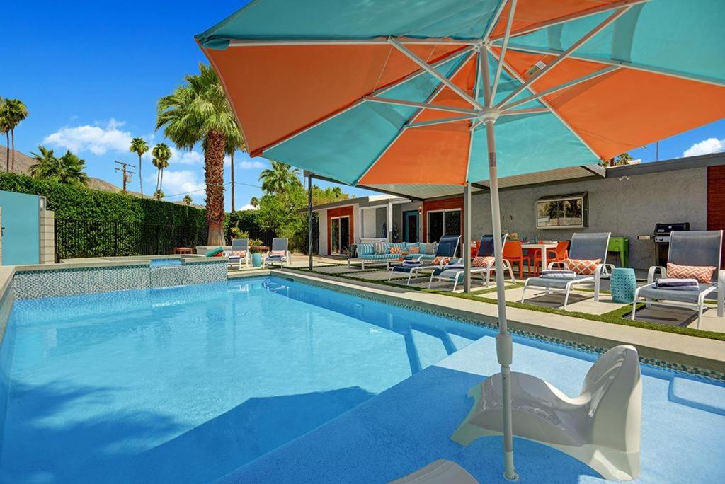 uma piscina com um guarda-sol e cadeiras e uma mesa em Shelby Sands em Palm Springs