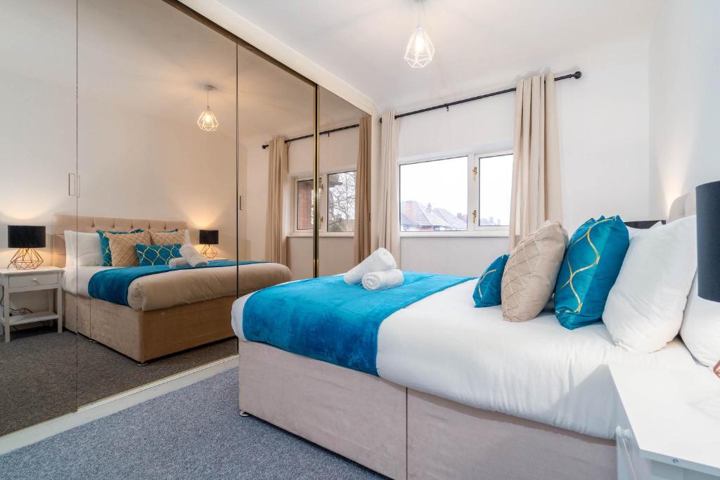 a bedroom with two beds and a mirror at 4 Bed House - Lots of Parking - Garden - Fast WIFI - Groups - Contractors - Excelled Value Accommodation - 802W in Birmingham