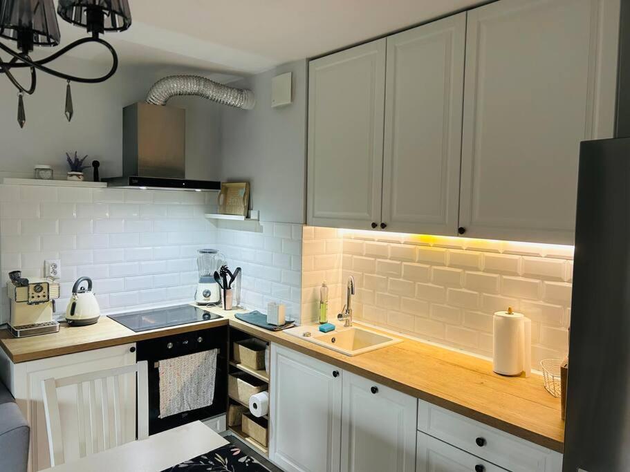 a kitchen with white cabinets and a wooden counter top at Komfortowy apartament Krokusowa 6 in Krakow