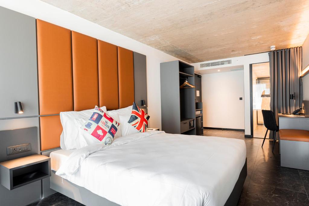 a bedroom with a large bed with an orange headboard at The Londoner Hotel St. Julian's in St. Julianʼs