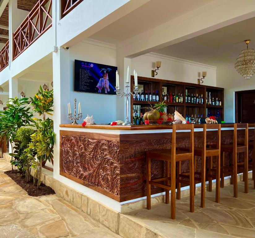 een bar in een villa met houten barkrukken bij Karibu Beach Resort in Pongwe