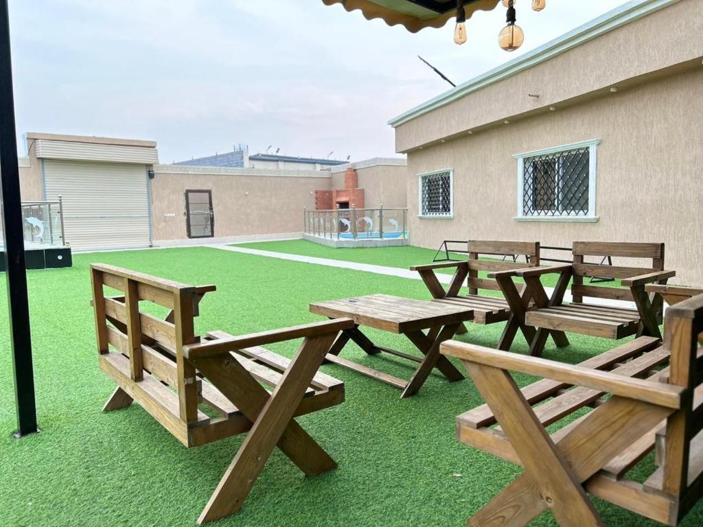 吉達的住宿－استراحة زهرة الاماكن (1)，一组野餐桌和草坪上的长椅