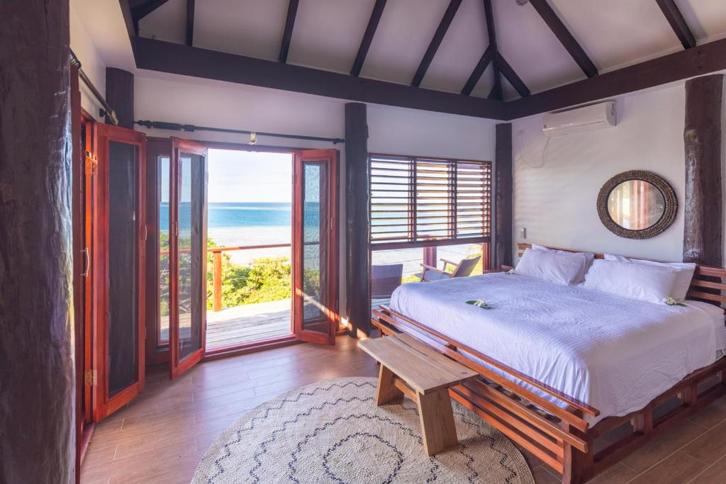a bedroom with a bed with a view of the ocean at Private Oceanfront Fijian Villa Sleeps 8 in Malolo