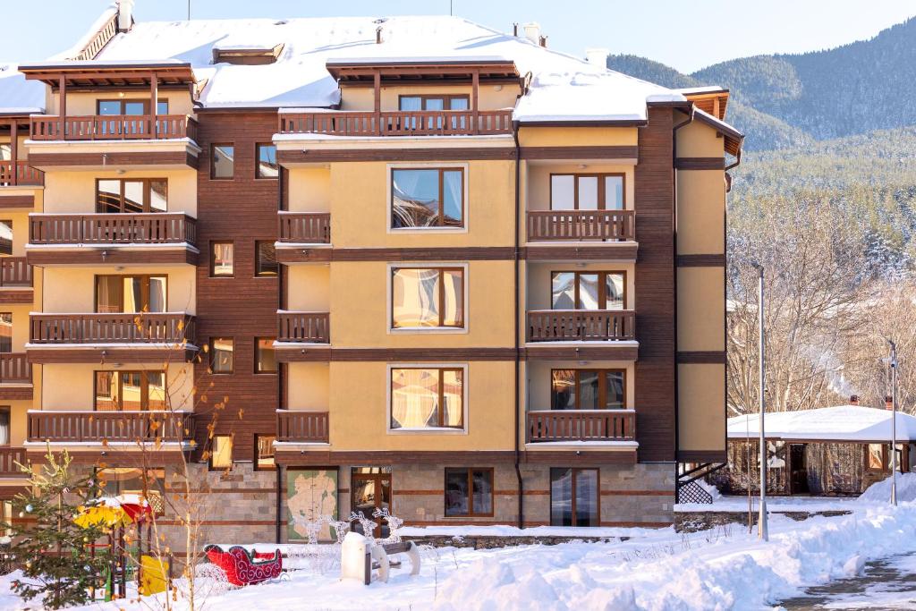 een gebouw met sneeuw op de grond ervoor bij Pirin Sense Apartment Complex in Bansko