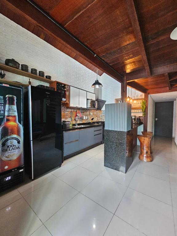 eine große Küche mit einer Flasche Bier auf dem Kühlschrank in der Unterkunft Charme do Chalé 17 em Gravatá in Gravatá