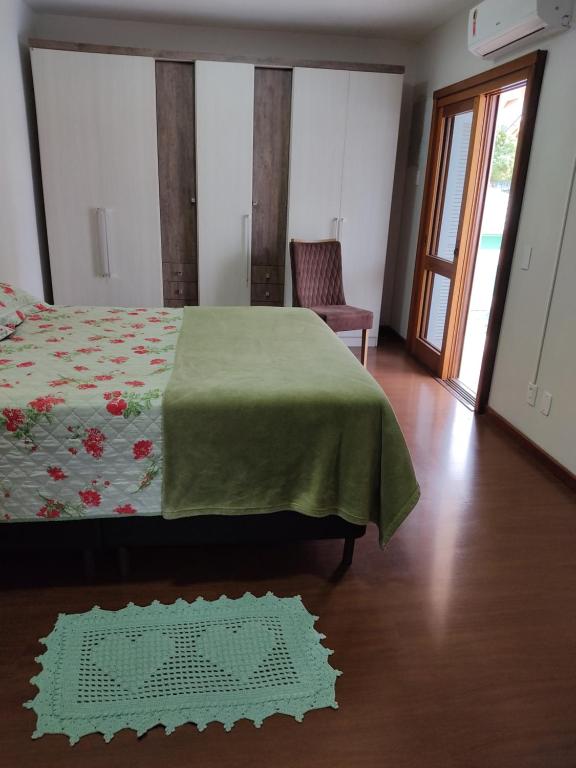 a bedroom with a bed with a green blanket and a chair at Nascer do Sol - Edelweiss in Nova Petrópolis