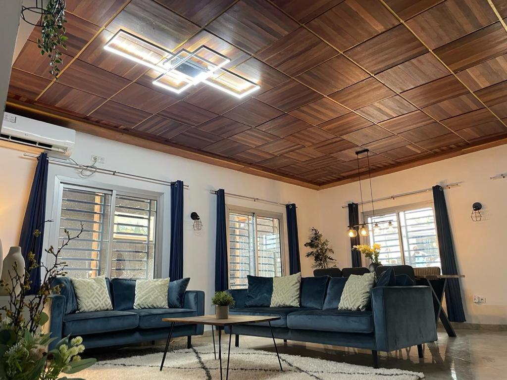 a living room with blue couches and a wooden ceiling at Mado Coliving - Studio Appart, Chambre coin cuisine, Chambre in Douala