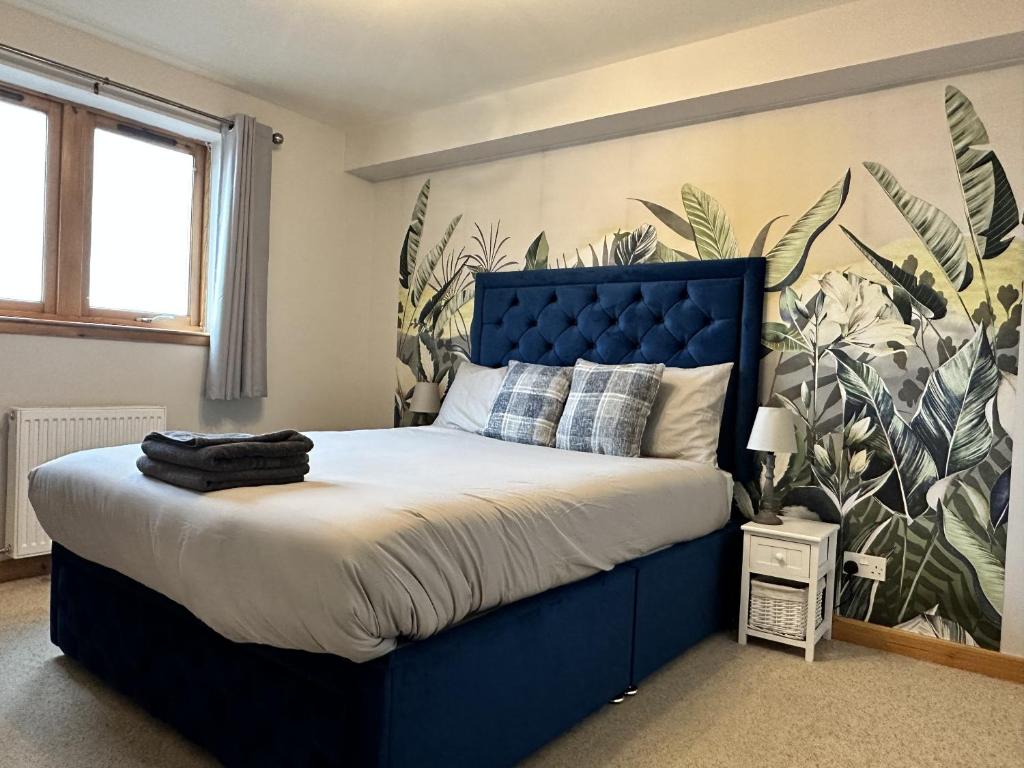 a bed with a blue headboard in a bedroom at Waterside View Apartment in Inverness